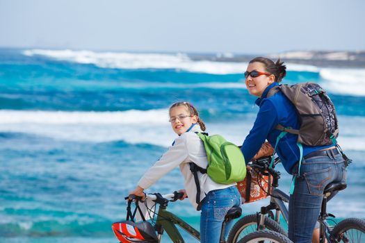 Girl with her mother having a weekend excursion on their bikes on a summer day in beautiful sea landscape