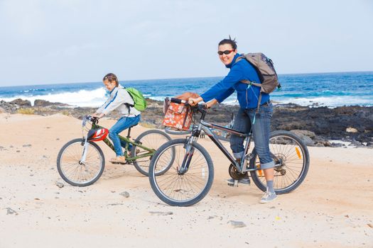 Girl with her mother having a weekend excursion on their bikes on a summer day in beautiful sea landscape