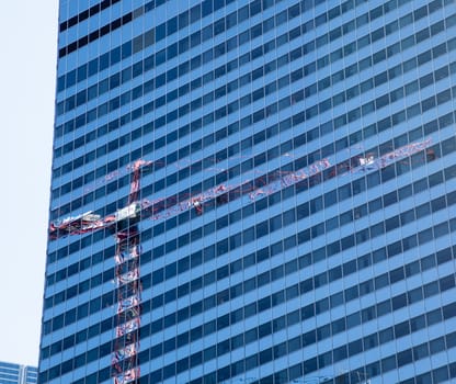 Reflection of construction crane in Chicago in the blue windows of a skyscraper opposite