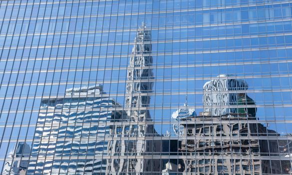 Reflection of old and new buildings in Chicago in the blue windows of a skyscraper opposite