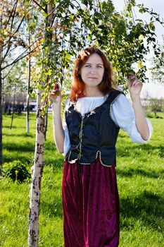 Medieval woman standing near the birch