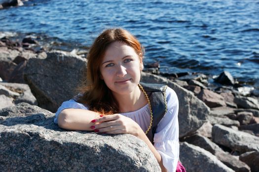 Young medieval woman on the rock near the sea