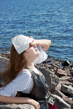 Young medieval woman on the rock near the sea