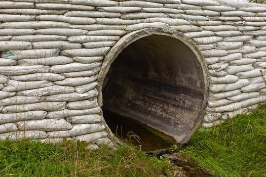 Large circular storm water culvert or drainage pipe infrastructure with concrete bank reinforcement