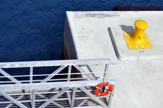 Concrete pier with yellow bollard and gangway