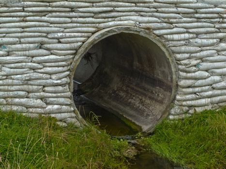 Large circular storm water culvert or drainage pipe infrastructure with concrete bank reinforcement