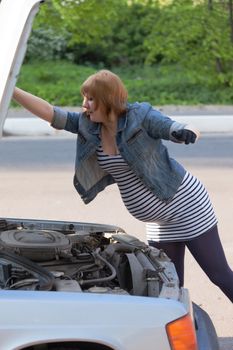 Pregnant Woman Opens the Hood of the Car