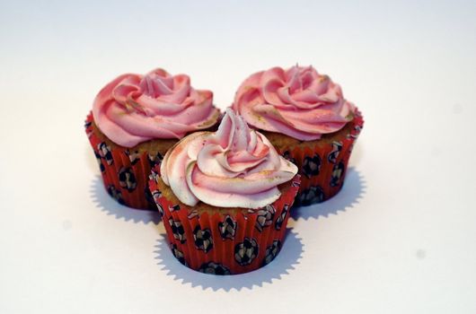 Three cupcakes with pink frosting on the stop, in red cases decorated with tiny footballs, against a white background with copy space.




Three cupcakes with pink frosting on the stop, against a white background with copy space.
