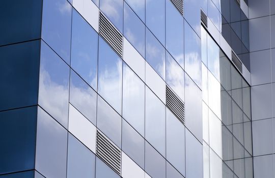 The ventilation grids, exterior facade of a building covered with glass reflections of the clouds taken. ventilation grills to be emphasized in this photograph and the glass-clad building on the original.