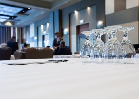 Conference table with glasses and pen paper with people in background