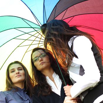 girlfriends stay under colourful umbrella 