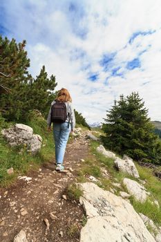 Young woman is walking on pathway in Italian Alps