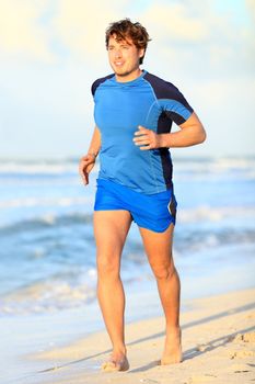 Running man. Male runner jogging on beach barefoot during outdoor sport fitness exercise. Caucasian male fitness model in his twenties