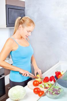 Young woman in kitchen cutting vegetables