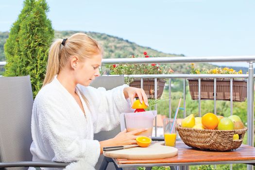 Woman making morning juice on terrace