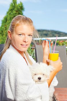Woman drinking morning juice on terrace with her dog