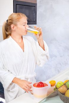 young woman drinking fresh juice in kitchen