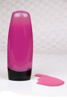 purple colored shower gel bottle and squeezed sample on grey background