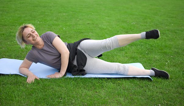 middle aged woman keeping fit with exercises in a park