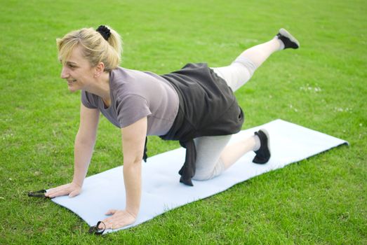 middle aged woman keeping fit with exercises in a park