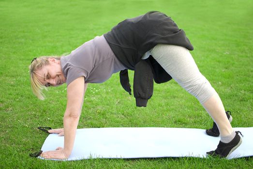 middle aged woman keeping fit with exercises in a park