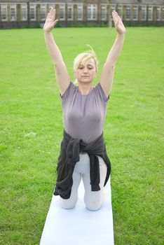 middle aged woman keeping fit with exercises in a park