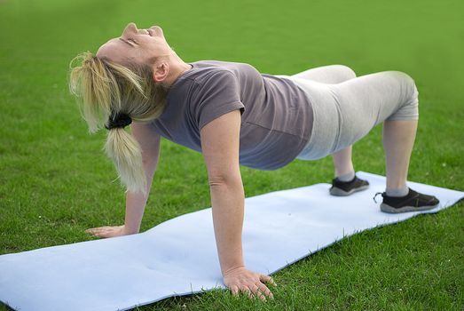 middle aged woman keeping fit with exercises in a park