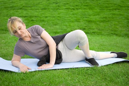 middle aged woman keeping fit with exercises in a park