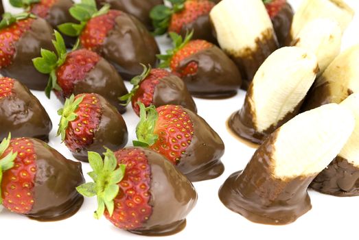 delicious strawberries and bananas covered with chocolate in a white plate