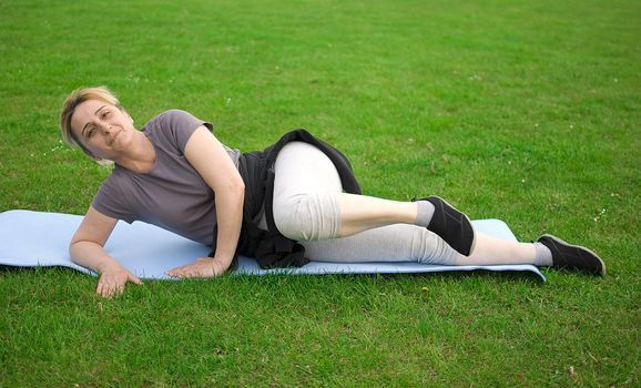 middle aged woman keeping fit with exercises in a park