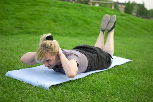 middle aged woman keeping fit with exercises in a park