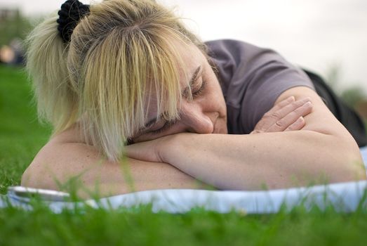 middle aged woman having a rest after exercises in a park