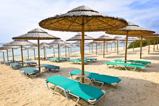 Straw umbrellas on empty seaside beach in Greece