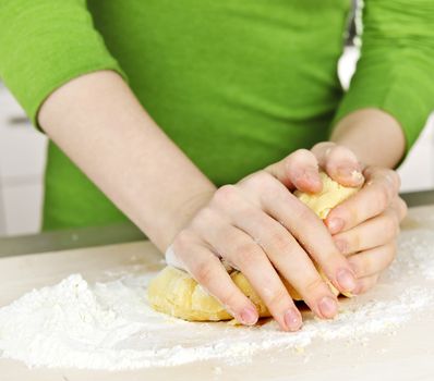 Hands kneading ball of dough with flour on cutting board