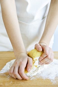 Hands kneading ball of dough with flour on cutting board
