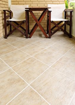 Wooden chairs and table on ceramic tile floor of balcony