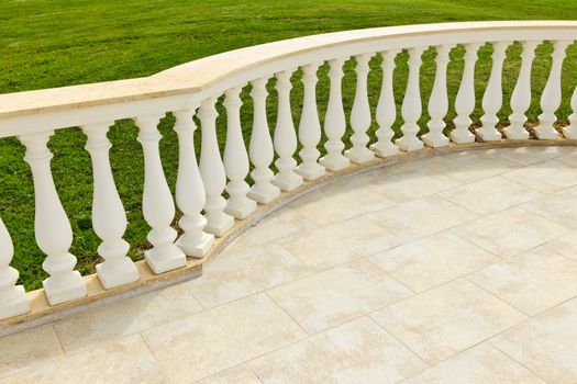 Fancy marble railing on ceramic tile patio with lawn