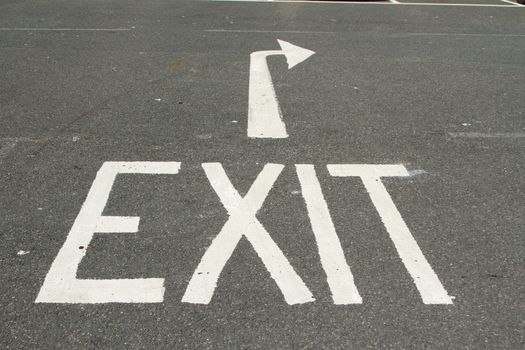 A tarmac road with the word, 'EXIT' and a directional arrow painted in white.