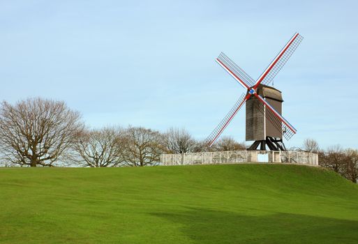 Windmill in Bruges, Belgium shot of green grass and blue sky background.