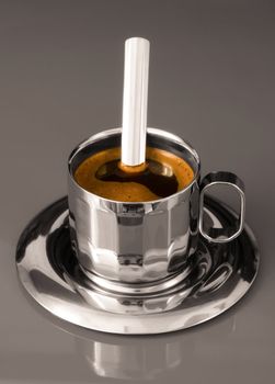 Close up of a metalic cup of coffee on grey background
