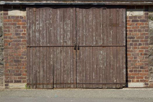 A wooden garage door with lock and handles and red brick walls.