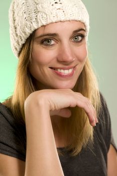 portrait of a happy woman with a winter cap in front of green background
