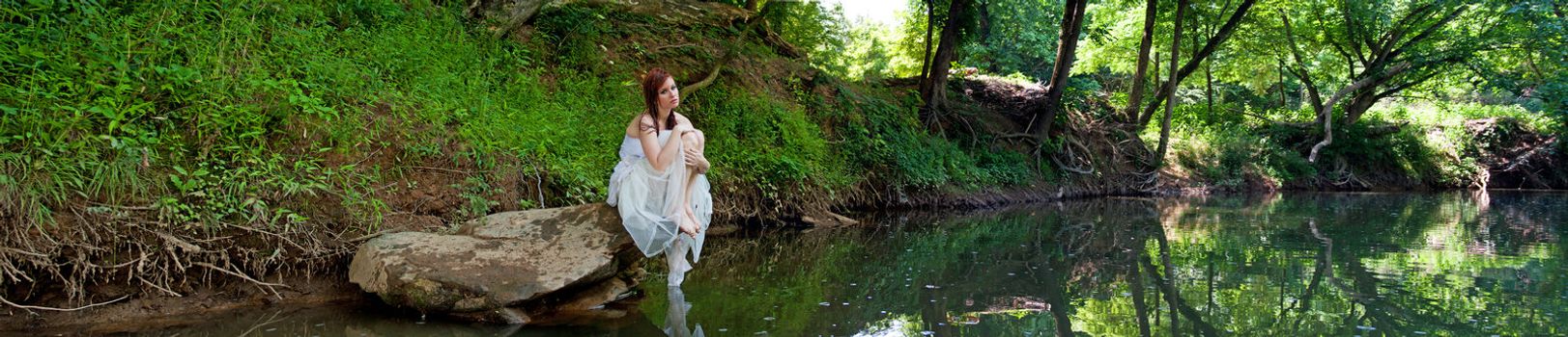 A sad bride sitting on a rock, panorama