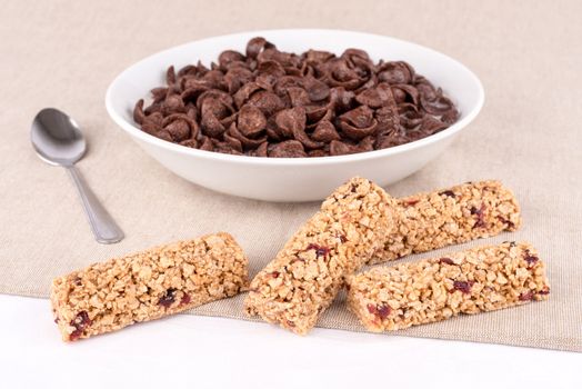 Dish with chocolate cereal flakes and bars with red  fruits.