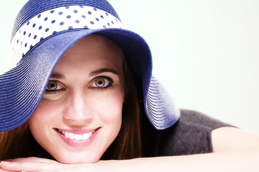 happy woman wearing a summer hat on light green background