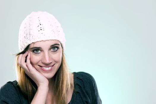 happy woman wearing a winter cap on light blue background