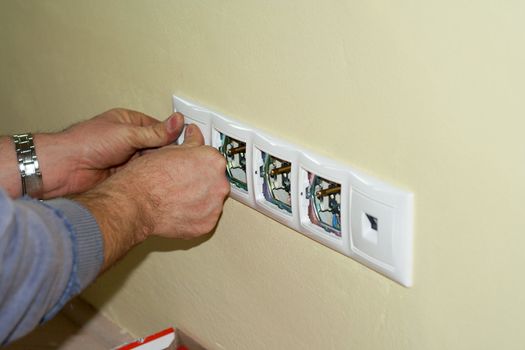 Electrician completes sockets on 230 volts into boxes in the wall. The sockets are in multiple frame together with LAN socket.