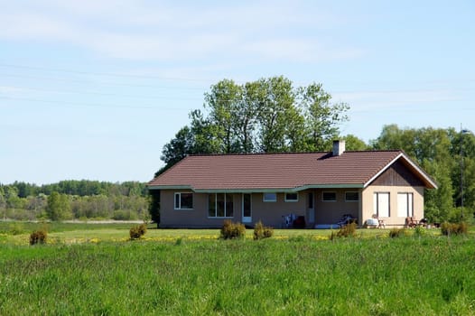 The house and field on a background of the blue sky