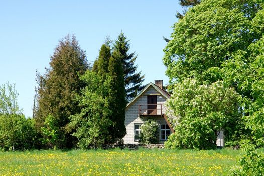 The brick house is behind green trees