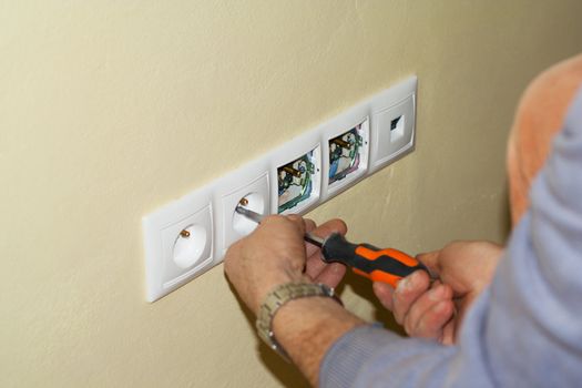 Electrician mounted outlet to 230 volts in a box in the wall with a screwdriver. The sockets are in the frame along with multiple PC connection LAN socket.